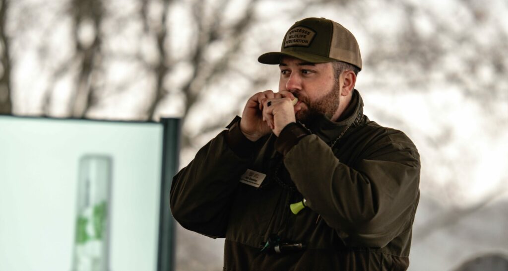 Instructor demonstrating how to blow a duck call at a waterfowl hunting workshop.