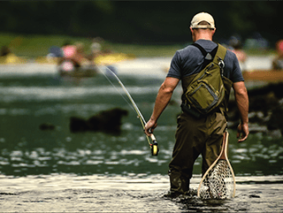 A man in waders fishing in the crowded river