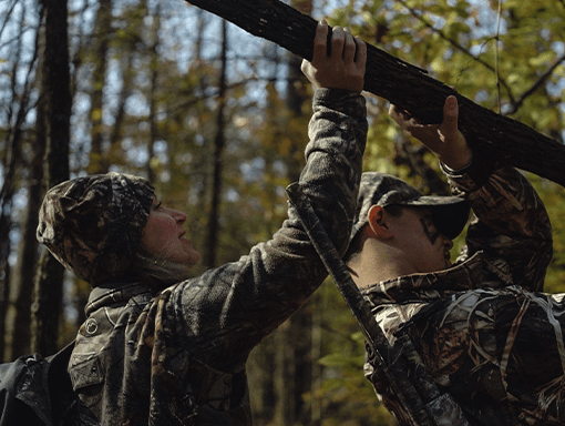 Two volunteers in camo help clear fallen limbs