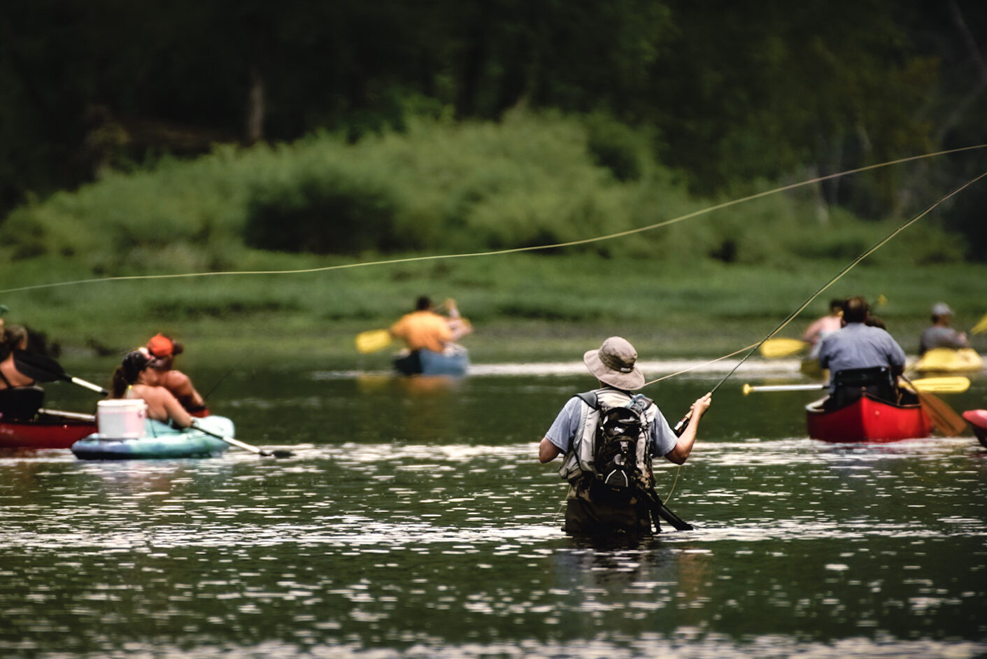 Fly fisherman surrounded by kayakers