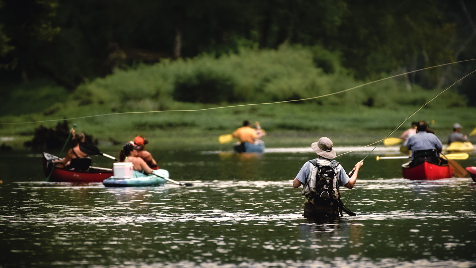 Fly fisherman surrounded by kayakers