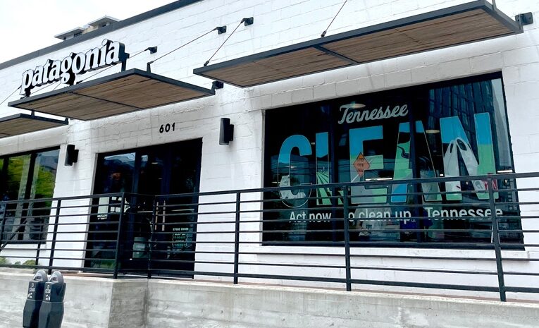 Storefront of Patagonia's Nashville location. A mural in the window says, "Tennessee CLEAN. Act now to clean up Tennessee." The word "CLEAN" after Tennessee is in block letters, which are filled in with images of wildlife, roads, agricultural fields, and other landscapes of Tennessee which are impacted by litter.